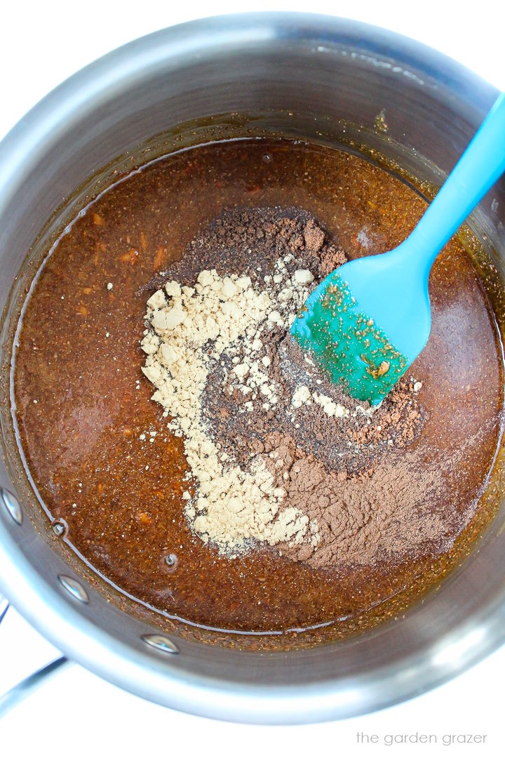 Preparing the liquid and spice mixture together in a medium saucepan with blue spatula 