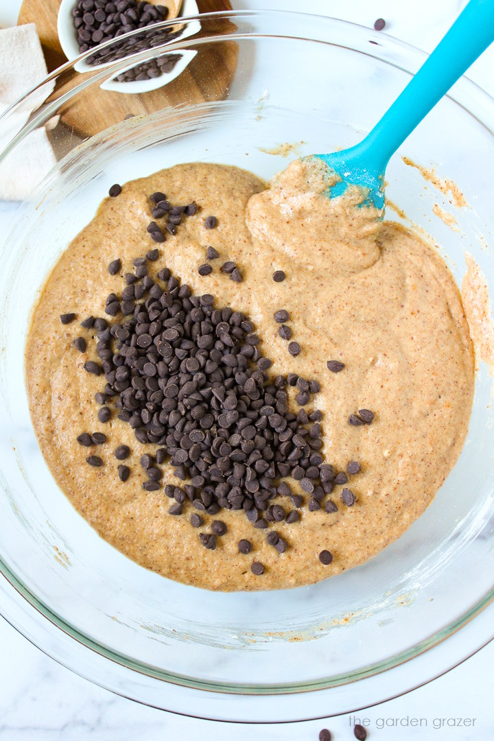 Overhead view of preparing muffin batter in a large glass mixing bowl with spatula