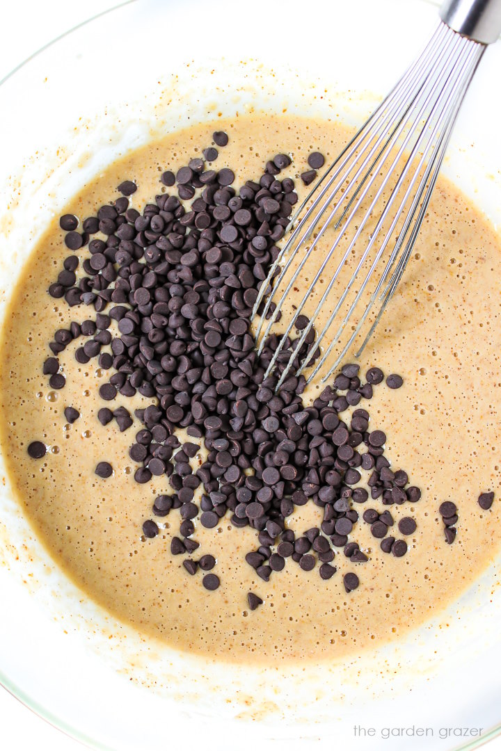 Overhead view of muffin batter being prepared in a large glass bowl with a whisk