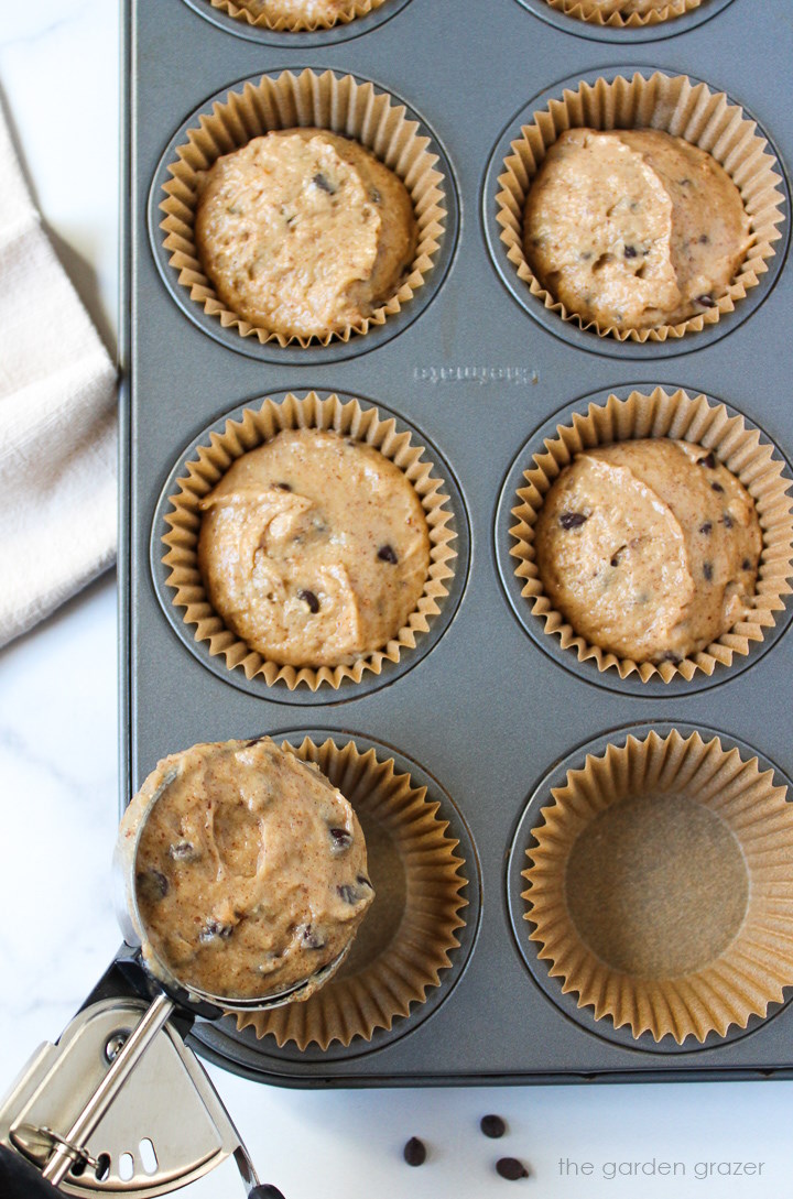 Scooping batter in a muffin tin with an ice cream scoop
