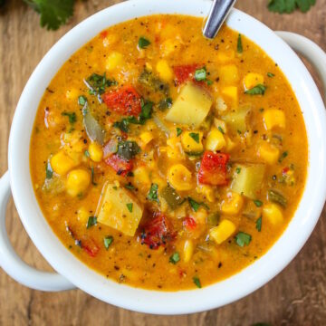 Overhead view of southwest corn chowder in a white bowl with serving spoon