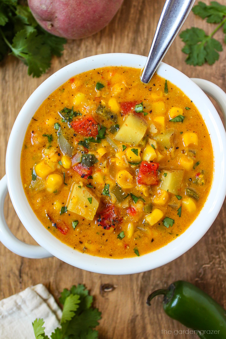 Overhead view of southwest corn chowder in a white bowl with serving spoon