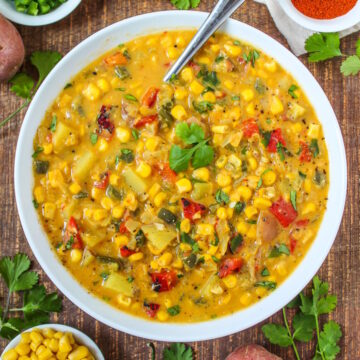 Vegan southwest corn chowder with roasted pepper, corn, and jalapeno in a white bowl garnished with cilantro