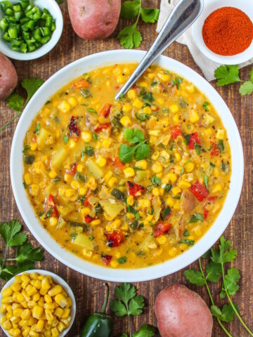 Vegan southwest corn chowder with roasted pepper, corn, and jalapeno in a white bowl garnished with cilantro