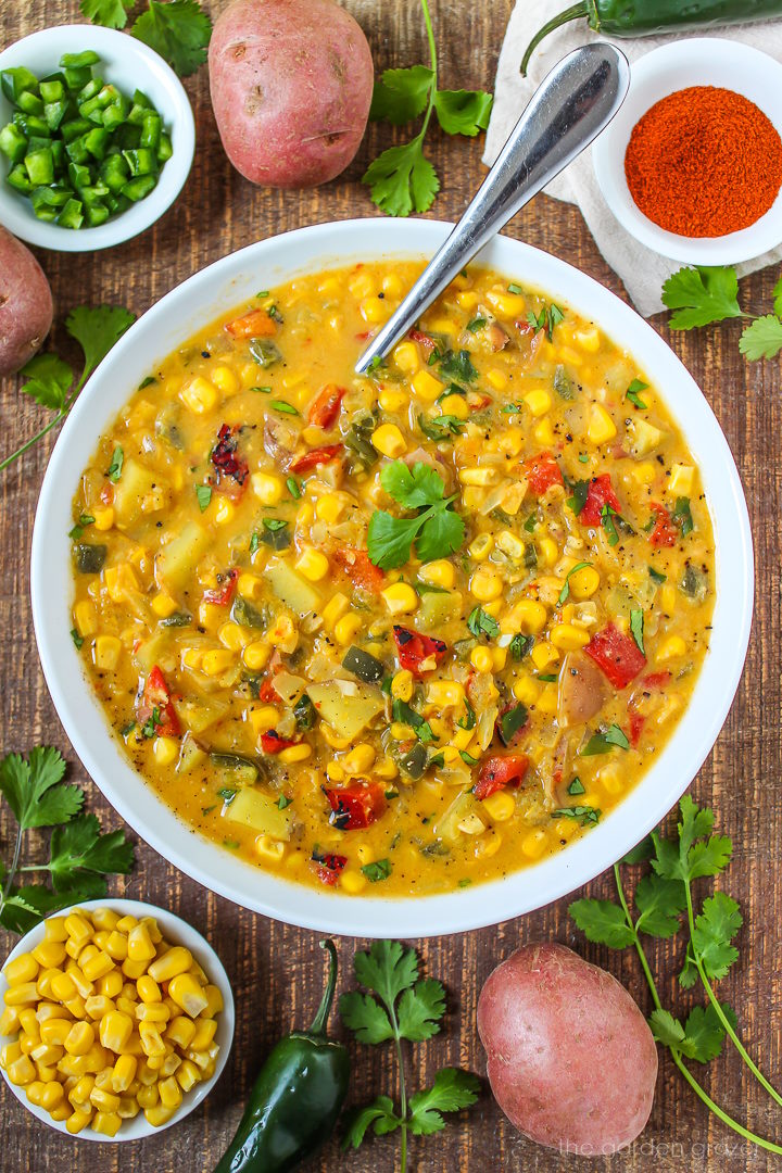 Vegan southwest corn chowder with roasted pepper, corn, and jalapeno in a white bowl garnished with cilantro