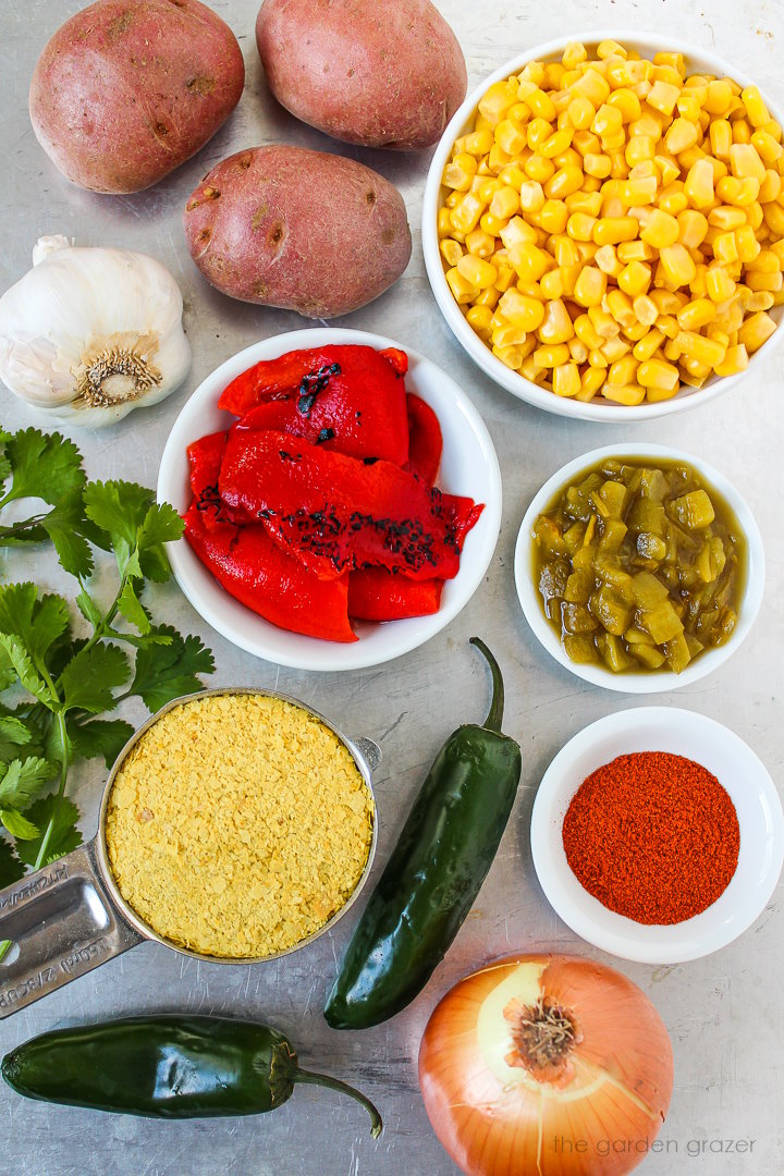 Sweet corn, potato, roasted pepper, green chiles, onion, garlic, and spice ingredients laid out on a metal tray