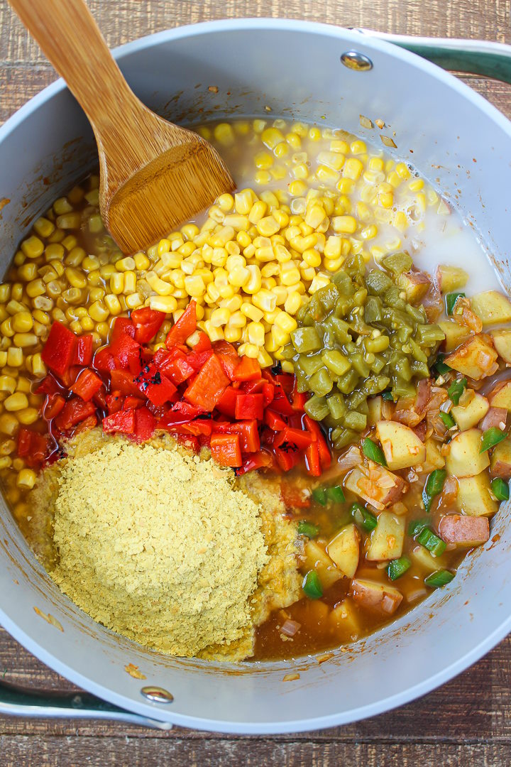 Overhead view of preparing ingredients for vegan chowder in a large pot before stirring together