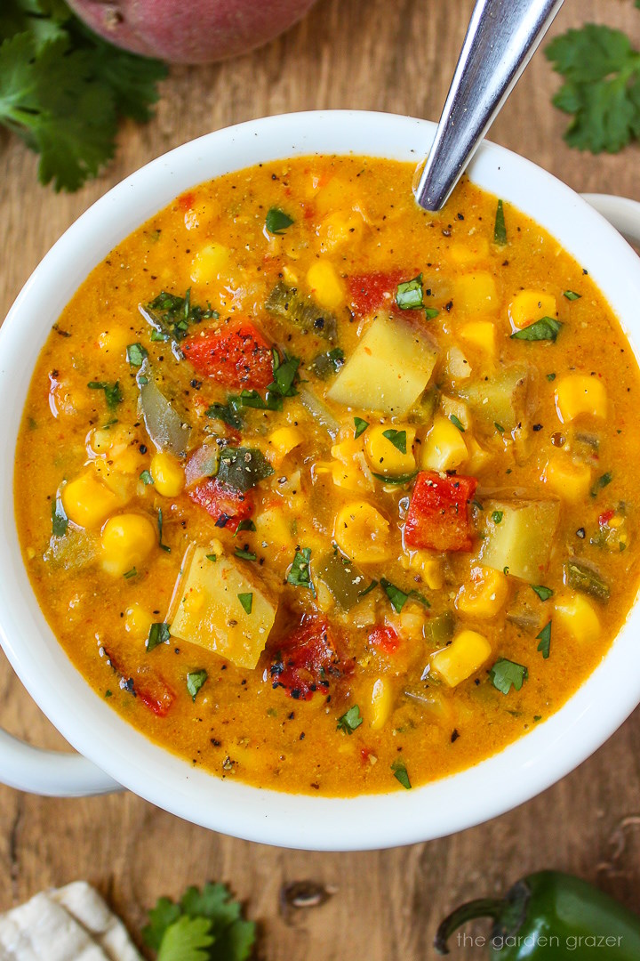 Close up view of southwest corn chowder in a white serving bowl with spoon