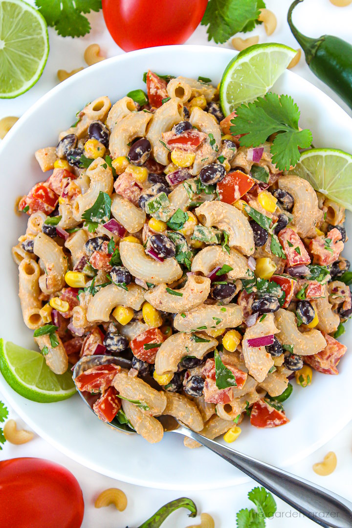 Overhead view of vegan southwest pasta salad with chipotle dressing in a white bowl garnished with cilantro and lime slices