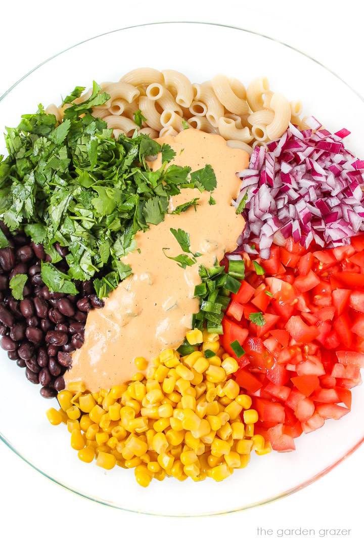 Overhead view of preparing salad ingredients in a large glass bowl before mixing together