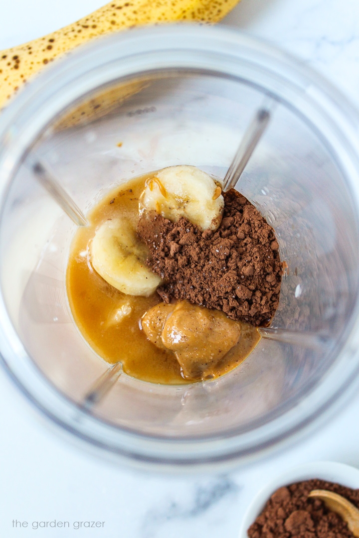 Overhead view of preparing smoothie ingredients in a small blender cup before blending together