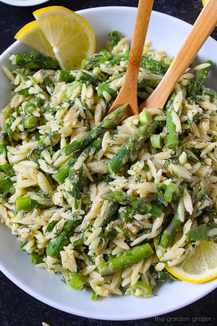 Overhead view of lemon asparagus orzo with fresh herbs tossed in lemon tahini dressing