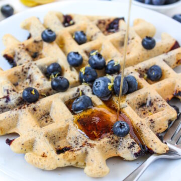 Close-up view of maple syrup being poured on a blueberry waffle
