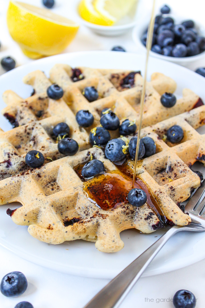 Close-up view of maple syrup being poured on a blueberry waffle