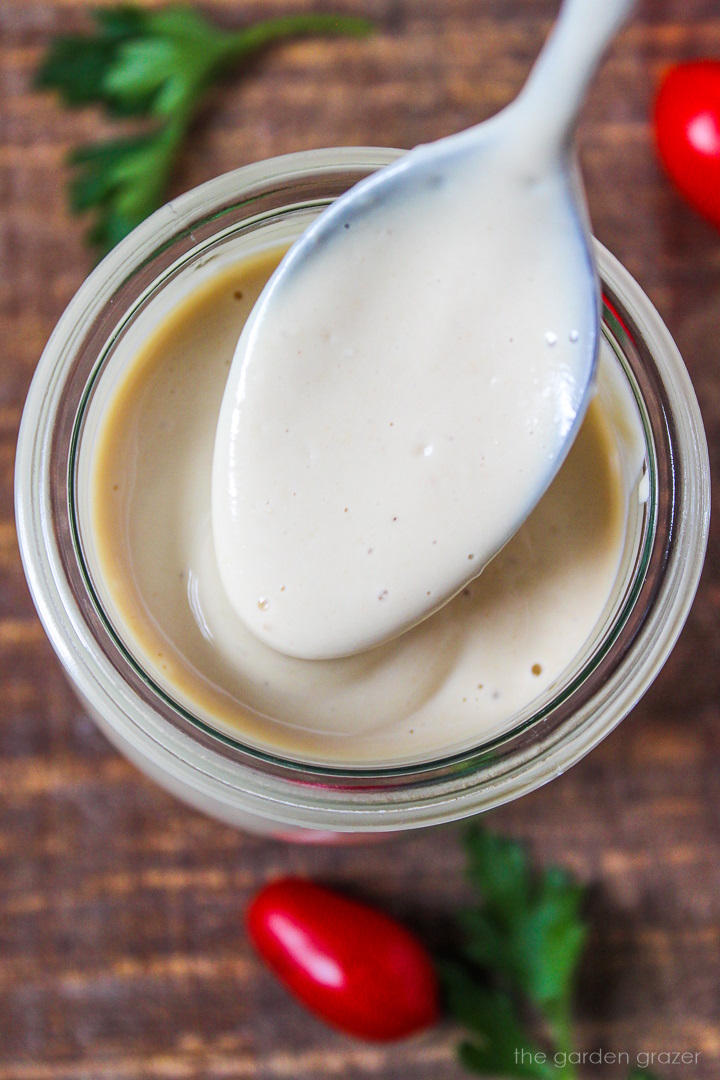 Overhead view of homemade dressing in a glass jar with spoon