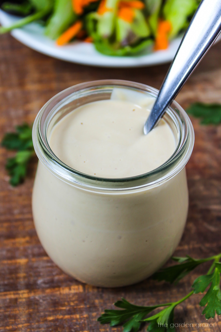 Lemon miso tahini dressing in a small glass jar with serving spoon