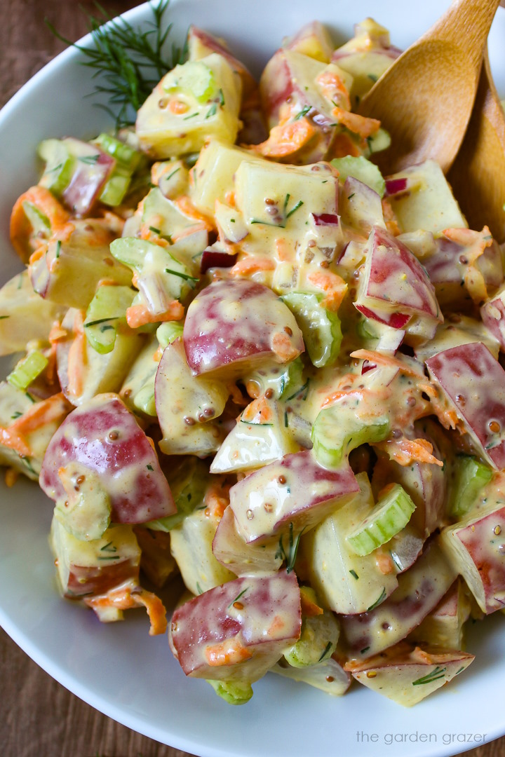 Close up view of vegan potato salad with dill in a white serving bowl