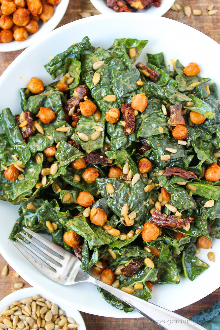 Kale and roasted chickpea salad on a white plate with serving fork