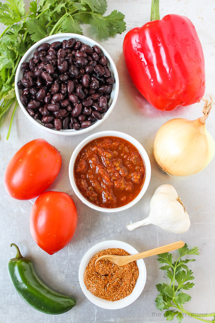 Red bell pepper, beans, salsa, tomato, onion, garlic, and seasoning ingredients laid out on a metal tray
