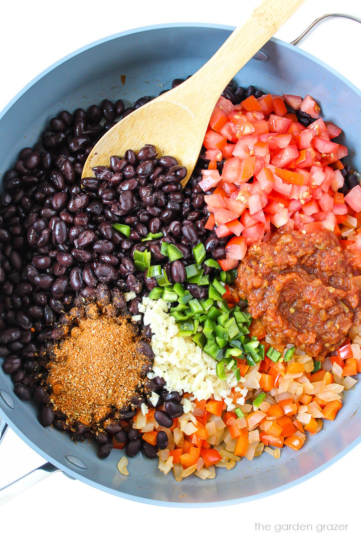 Overhead view of preparing ingredients in a large skillet for black bean burrito mixture