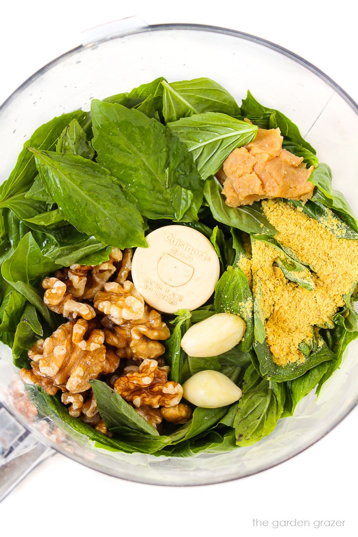 Overhead view of preparing pesto ingredients in a food processor before blending together