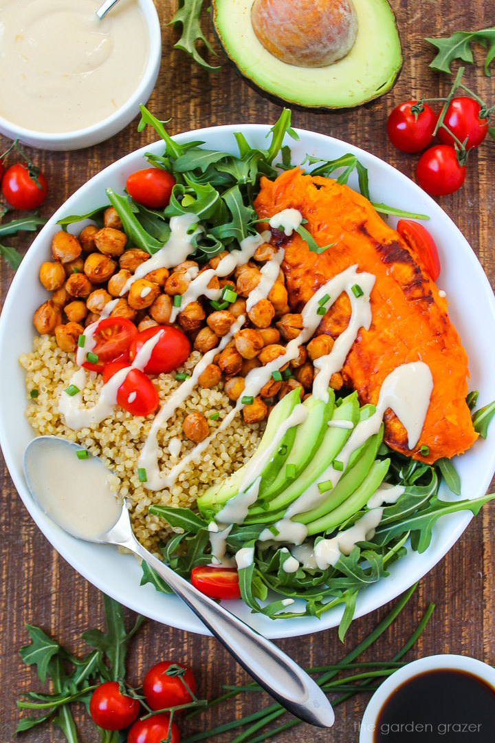 Close up view of quinoa sweet potato bowl drizzled with tahini dressing