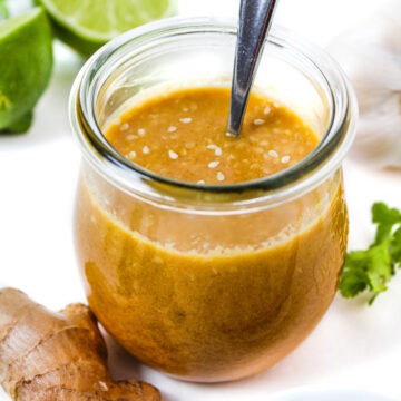 Asian sesame ginger dressing in a small glass jar with serving spoon