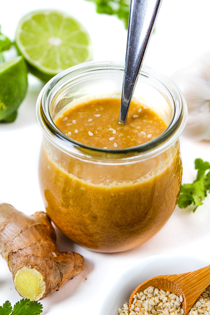 Asian sesame ginger dressing in a small glass jar with serving spoon