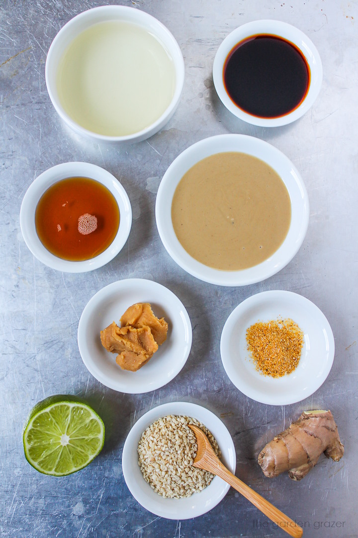 Rice vinegar, tamari, tahini, miso, lime, ginger, and garlic powder ingredients laid out on a metal tray