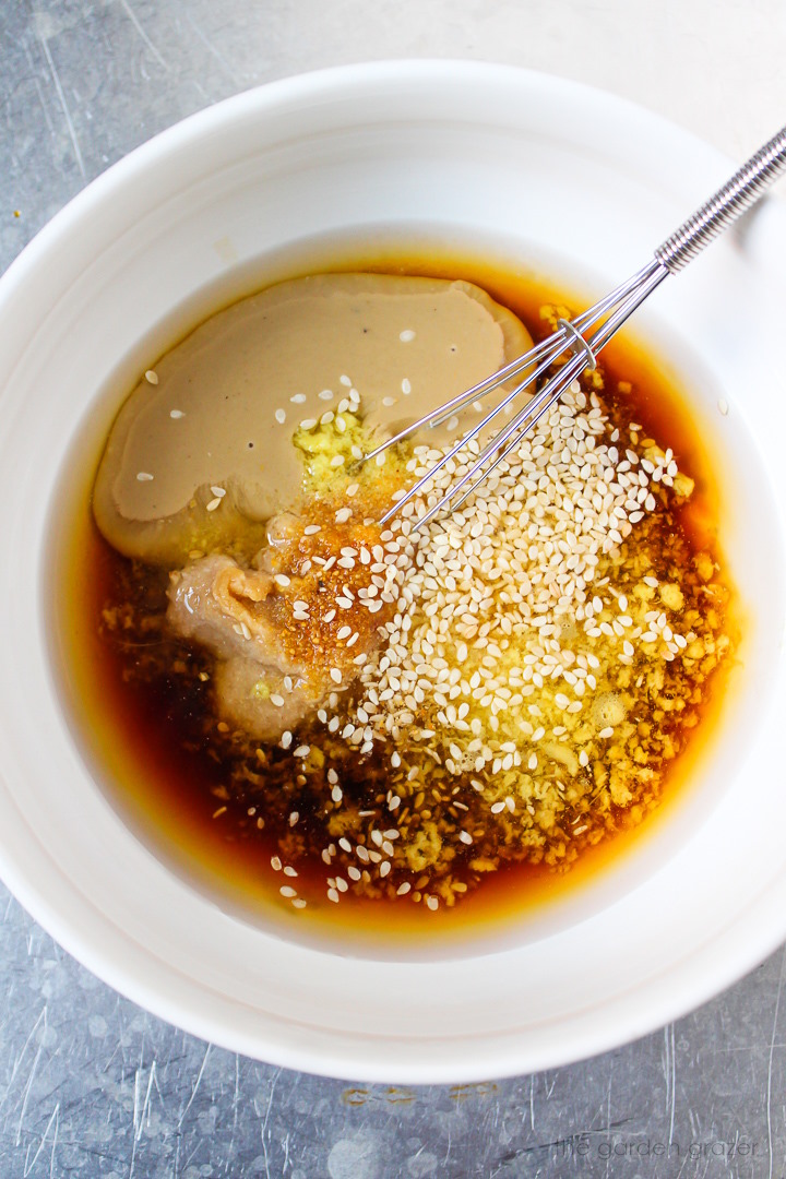 Overhead view of preparing dressing ingredients in a white bowl before whisking