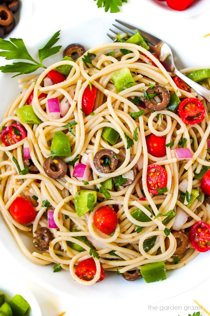 Close up view of spaghetti pasta salad with veggies on a white plate