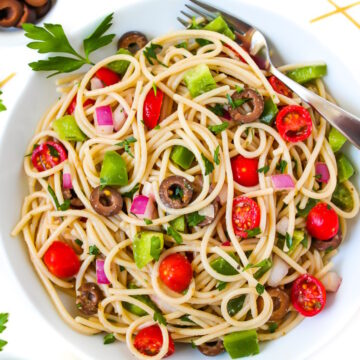 Overhead view of spaghetti salad in a white bowl with serving fork