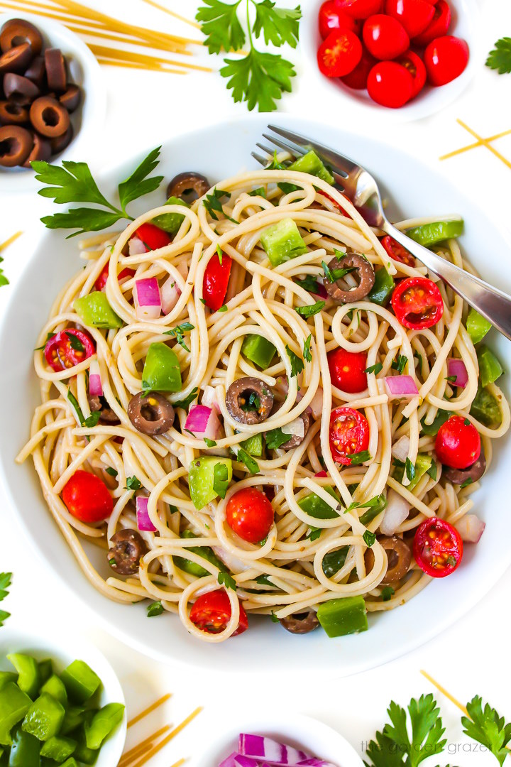 Overhead view of spaghetti salad in a white bowl with serving fork