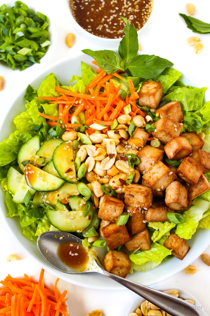 Tofu salad with cucumber, carrot, peanuts, and a savory dressing on a white serving plate