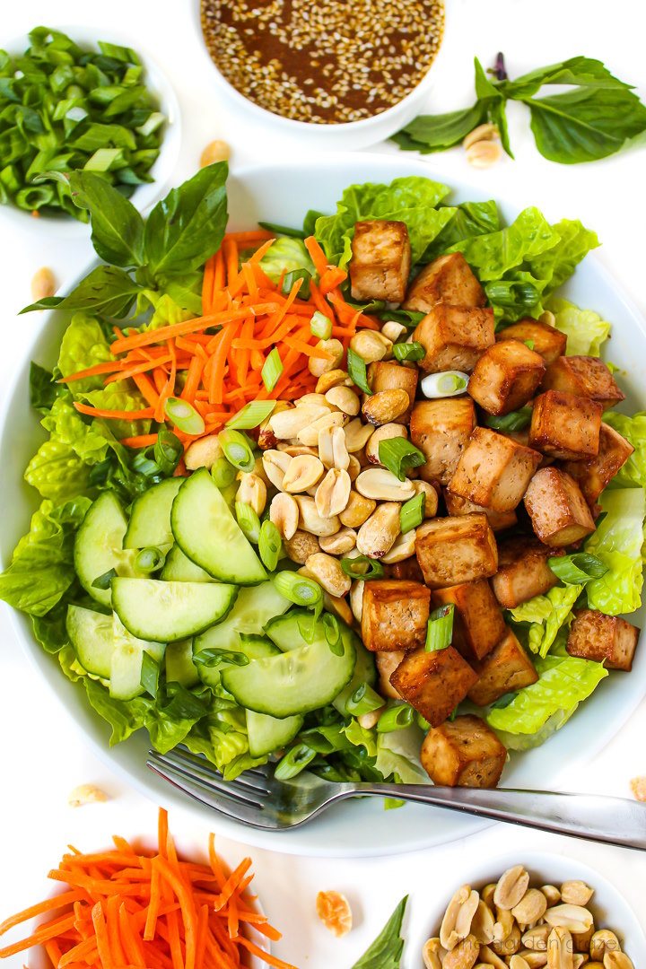 Overhead view of preparing salad components in a large white serving bowl