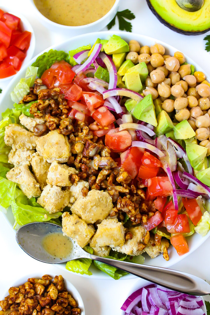 Close up view of vegan Cobb salad in a white bowl with nut bacon and chickpeas