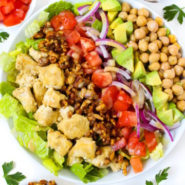 Overhead view of vegan Cobb salad with vinegar dressing in a large white serving bowl