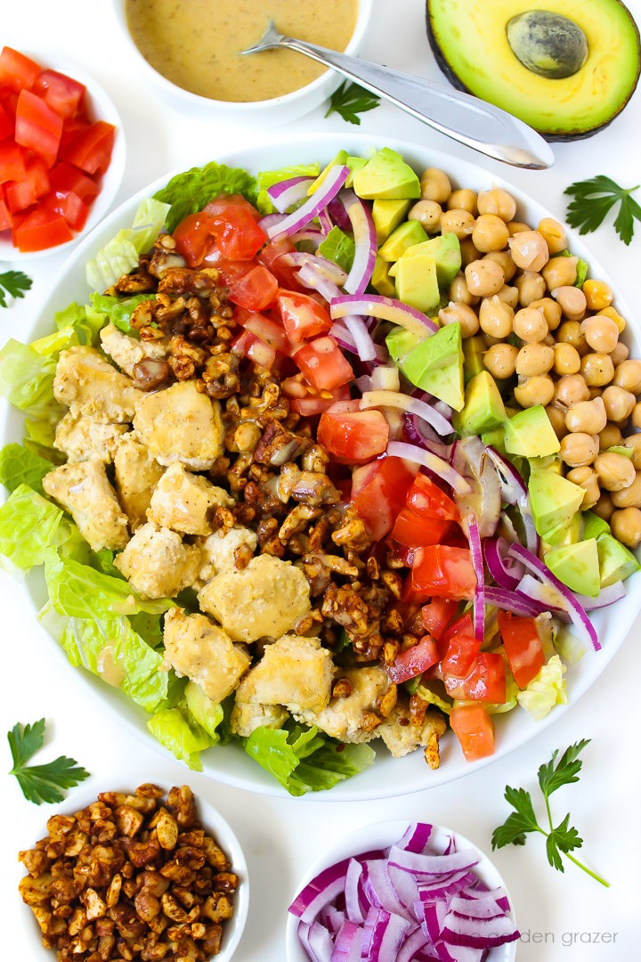 Overhead view of vegan Cobb salad with vinegar dressing in a large white serving bowl
