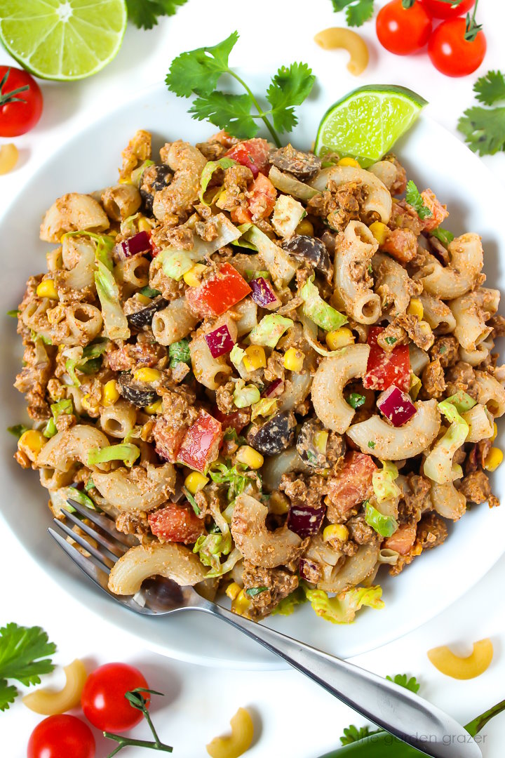 Overhead view of vegan taco pasta salad served in a white bowl with cilantro and lime