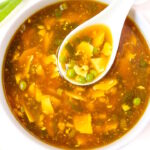 Vegan egg drop soup with serving spoon in a white bowl