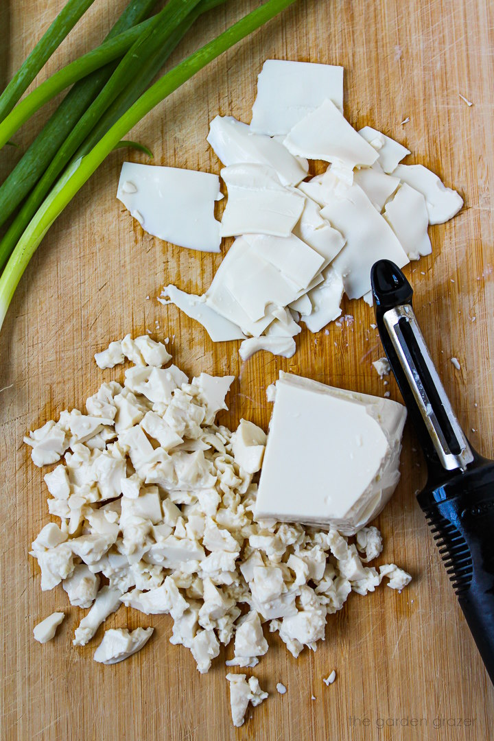 Preparing silken tofu ribbons with a vegetable peeler on a wooden cutting board