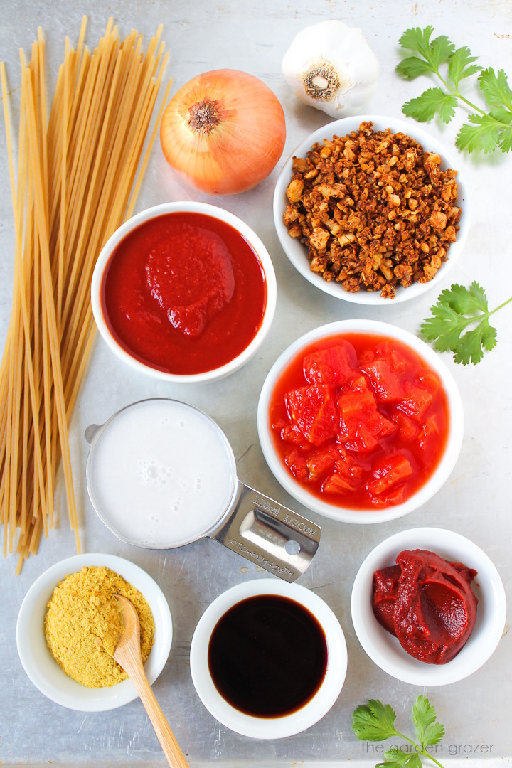 Pasta, tomato sauce, diced tomatoes, onion, garlic, chickpea-walnut crumbles, and tamari ingredients laid out on a metal tray