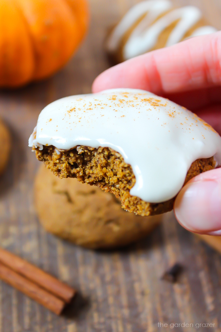 Close-up view of a bite taken out of a frosted vegan pumpkin cookie