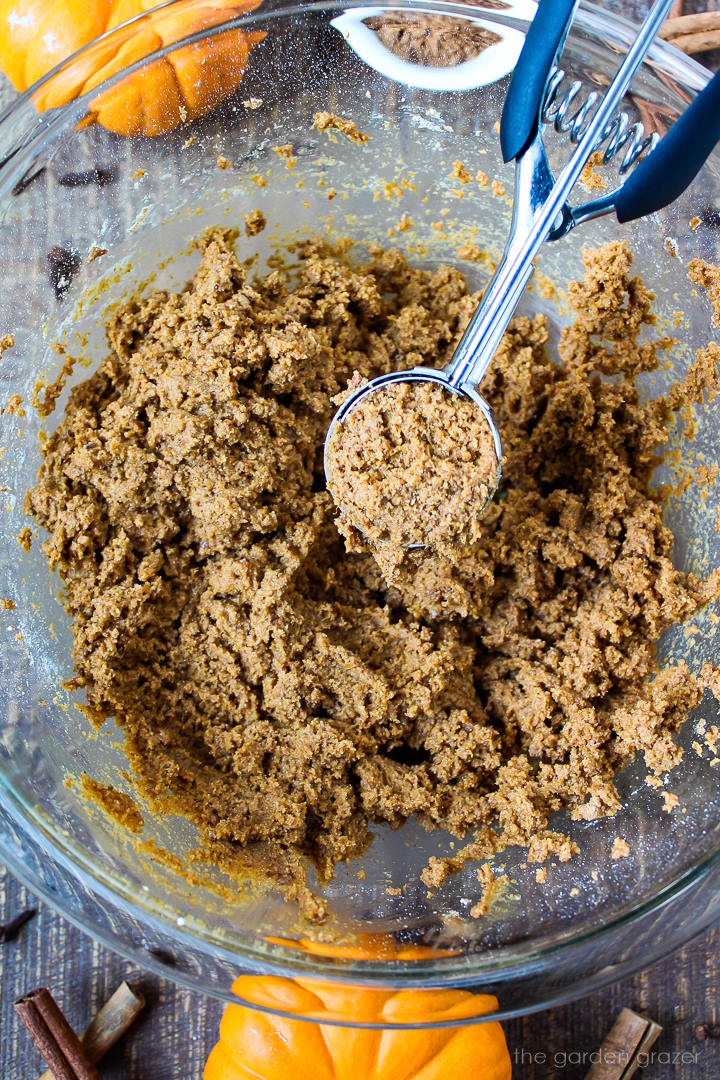 Overhead view of preparing cookie dough in a large mixing bowl with a metal scoop