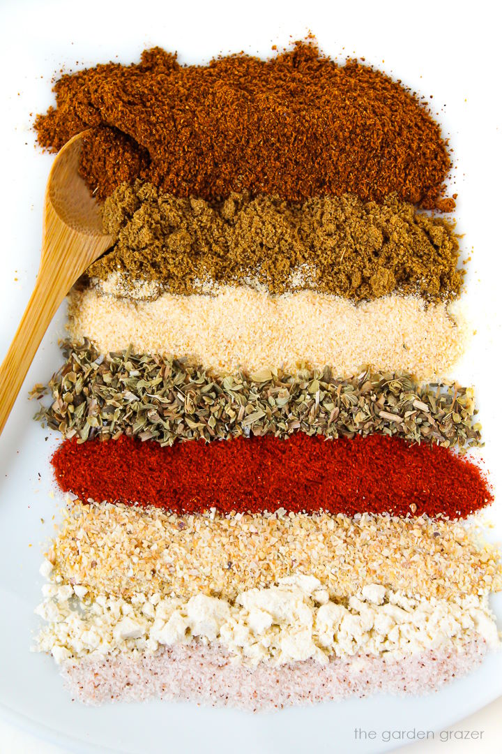 Chili seasoning spices lined up on a white plate before mixing together