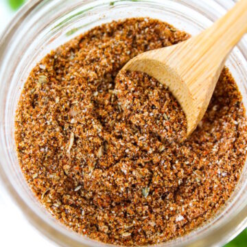 Overhead view of chili seasoning recipe mixed together in a small glass jar with wooden spoon