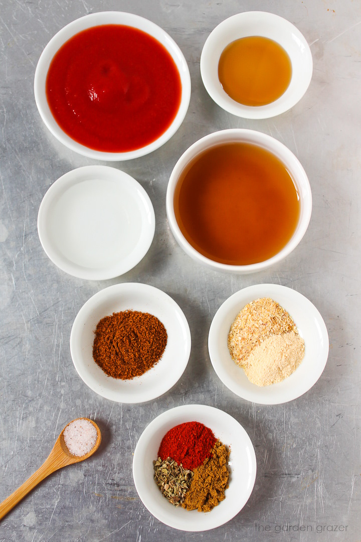 Tomato puree, vegetable broth, vinegar, salt, and seasoning ingredients laid out on a metal tray