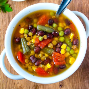 Overhead view of easy vegan soup in a white serving bowl with spoon