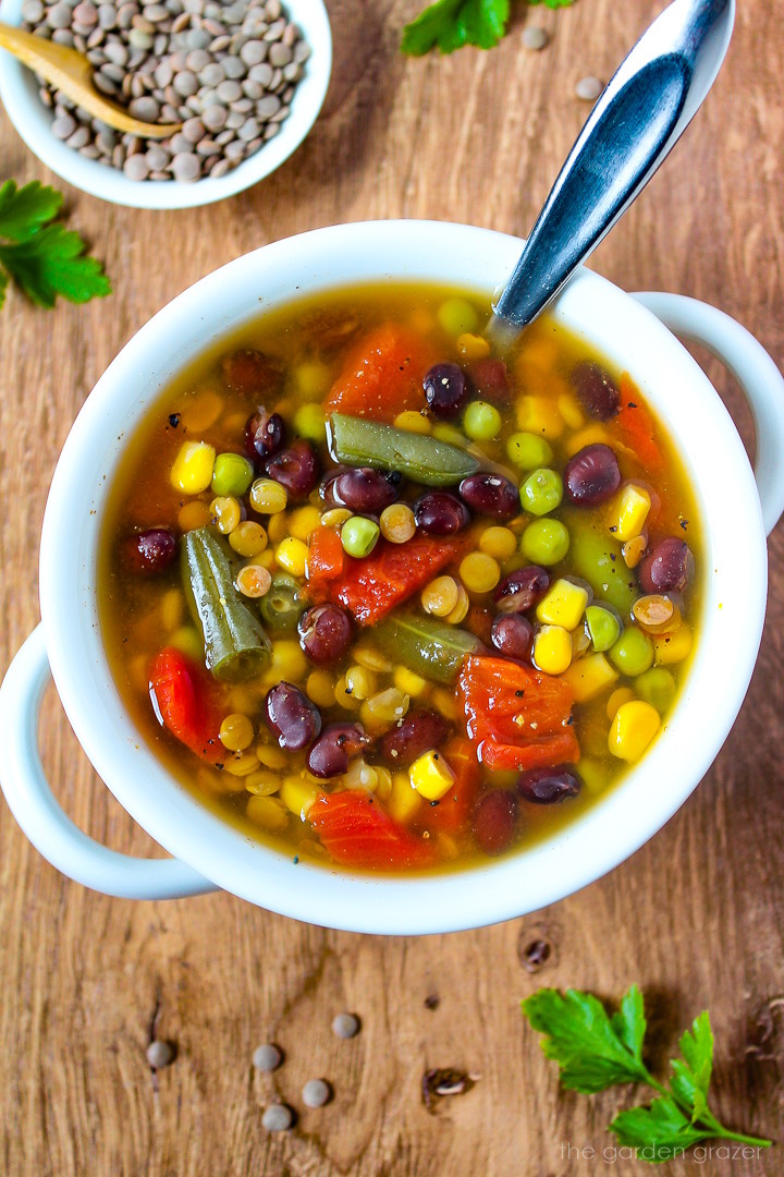 Overhead view of easy vegan soup in a white serving bowl with spoon