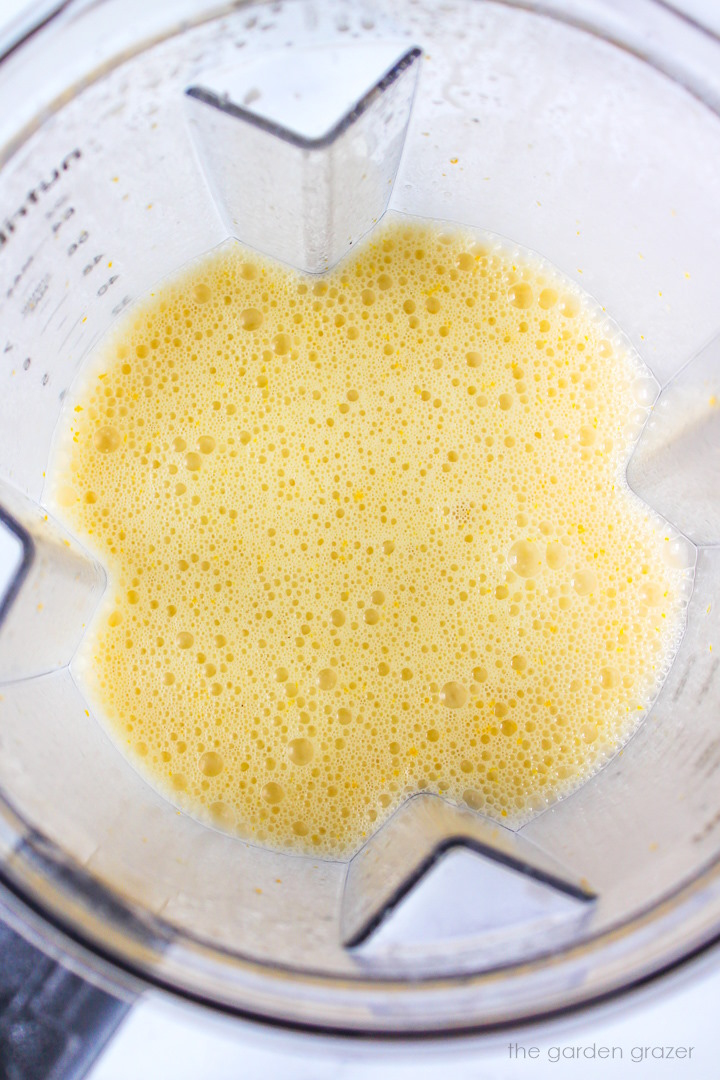 Overhead view of vegan orange creamsicle popsicle liquid blended in a large blender